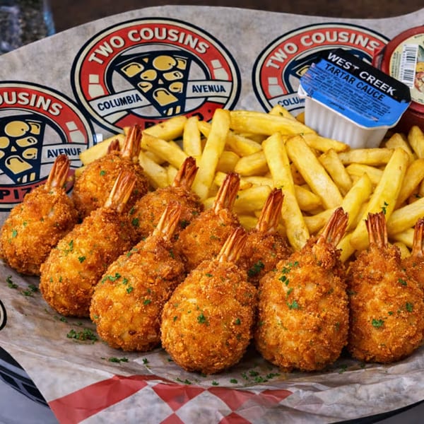 Two Cousins Pizza breaded shrimp and french fries with tartar sauce on branded paper.