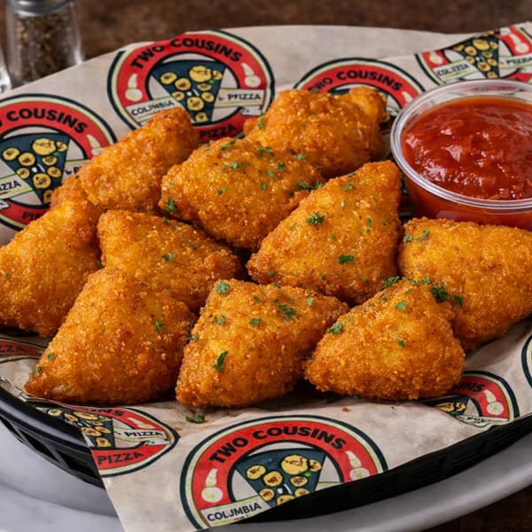 A basket of golden-brown fried ravioli from Two Cousins Pizza, garnished with parsley and served with marinara sauce.