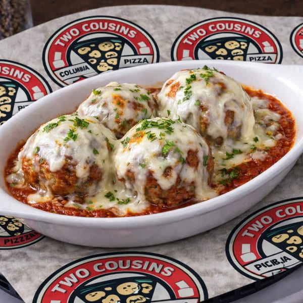 Four cheesy meatballs in marinara sauce, garnished with parsley, in a white dish on a branded paper.
